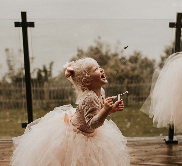 Flower girl in a peach tutu blowing bubbles