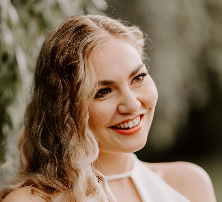 Bride with long wavy relaxed wedding hair, wearing a halterneck jumpsuit for tropical theme wedding