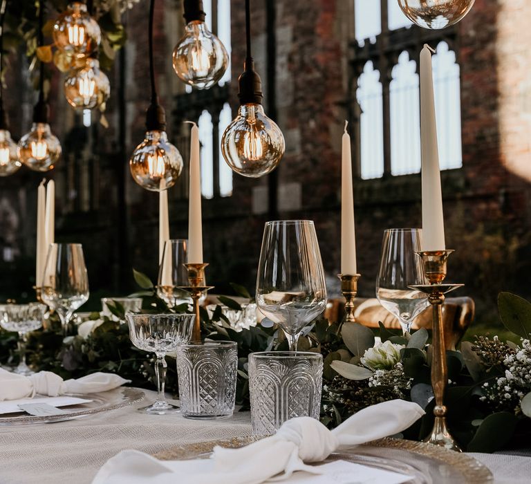 Elegant wedding table glassware, gold candlesticks and foliage table runner 