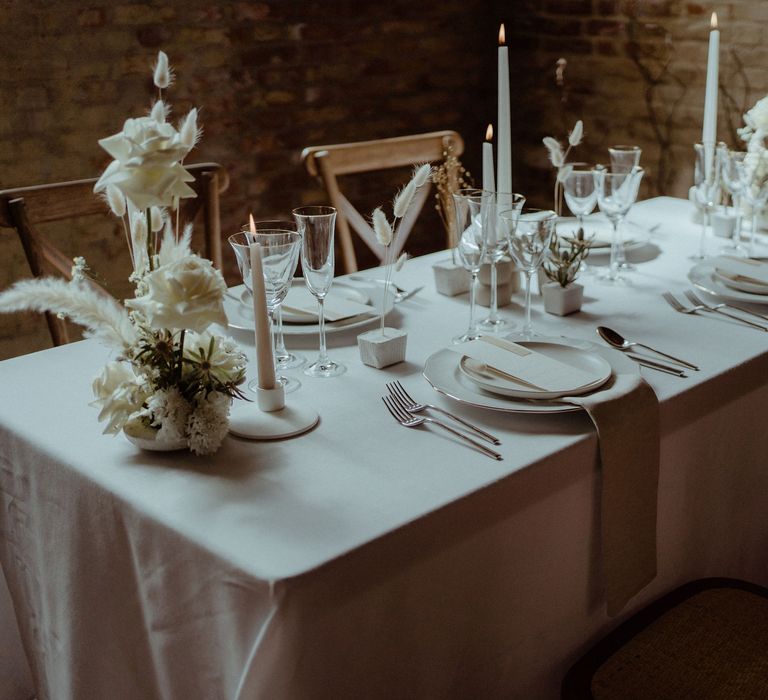 Minimalist decor for a simple elegant wedding table including dried grasses, bunny tails and white ceramics.