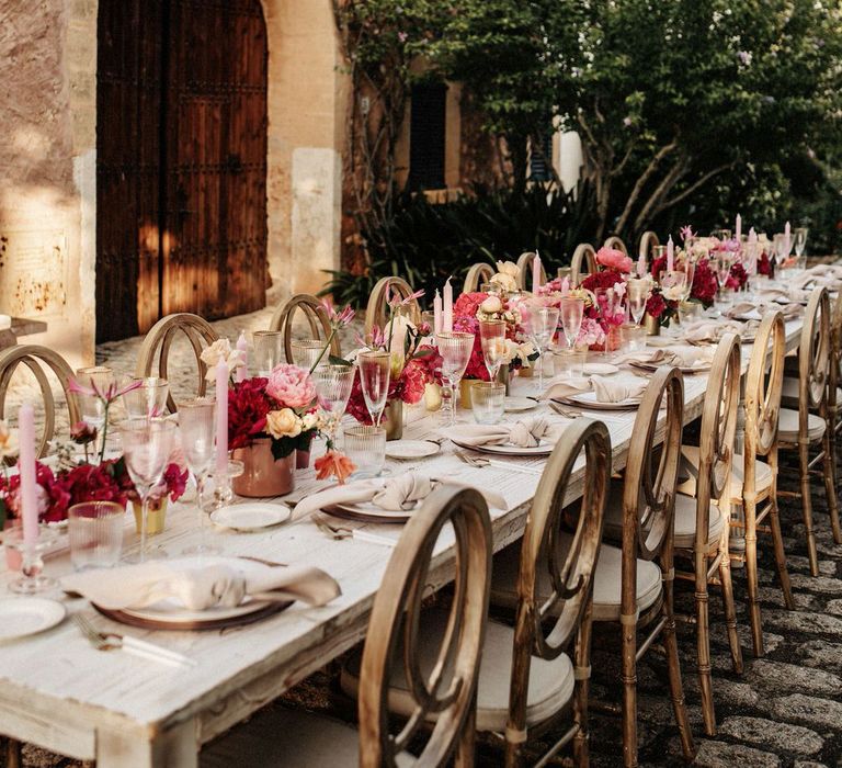 Stunning white, neutral and gold table with pink floral centrepieces and pink tapered candles