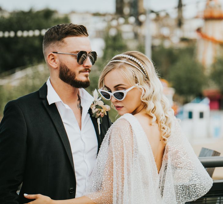 Stylish bride and groom in white cat eye and aviator sunglasses for coastal wedding 