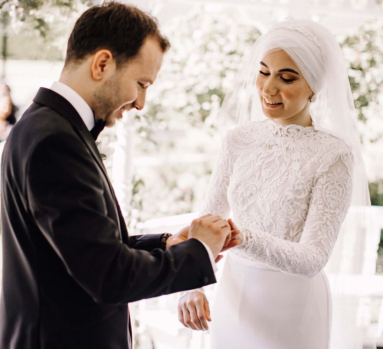 Groom puts on the bride's wedding ring who stunning bridal hijab