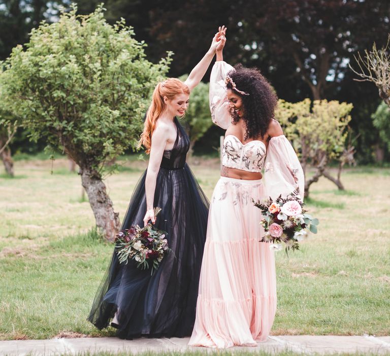 Wedding portrait of an neurodiverse couple in a black tulle wedding dress and blush pink separates dancing in a field 