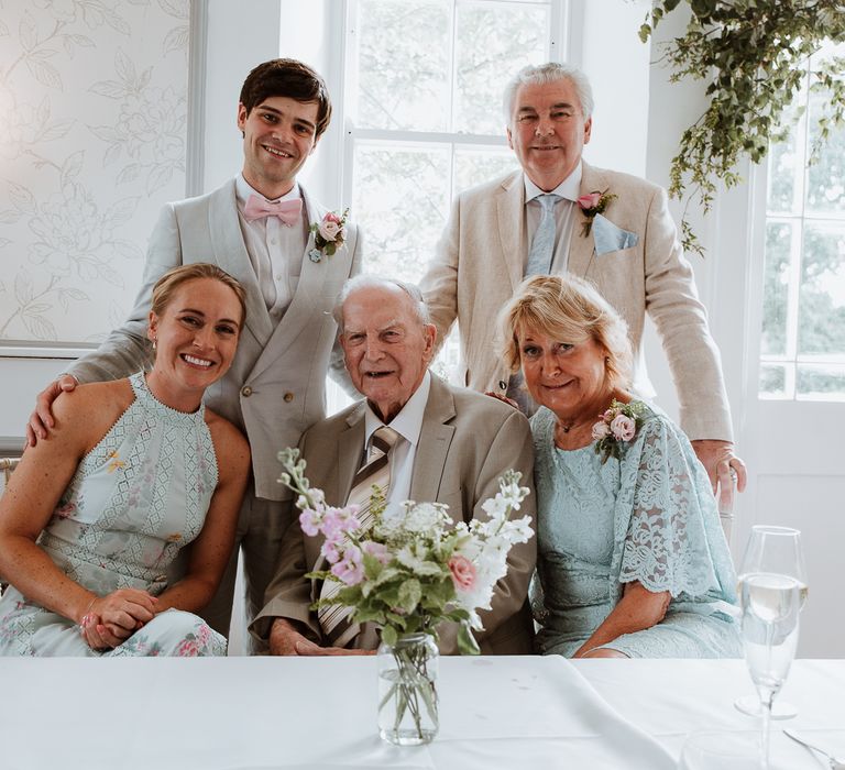 Bride & groom stand with their family on the day of their wedding 