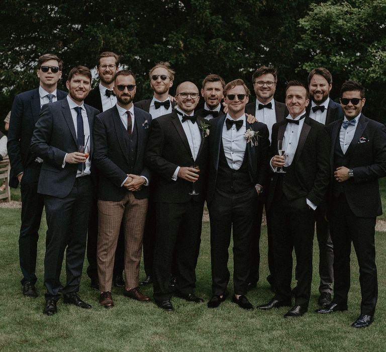 Groom stands with his groomsmen on the day of wedding in black tie