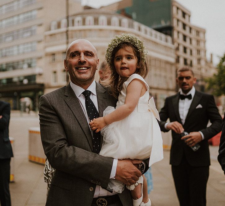 Wedding guests holding the flower girl in a tulle skirt dress and flower crown 