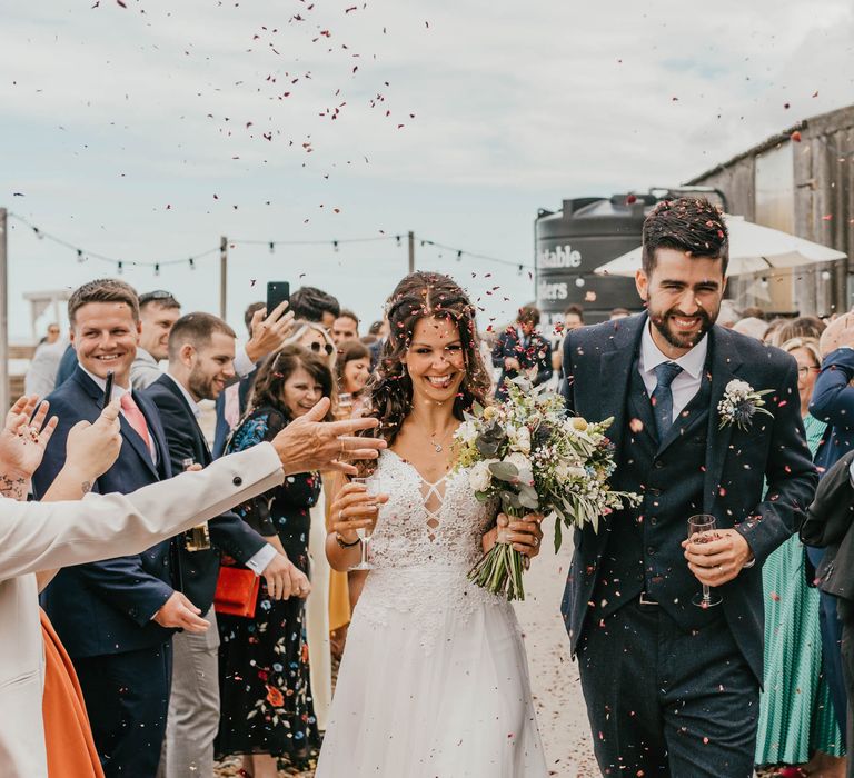 Bride & groom walk through confetti outdoors on their wedding day