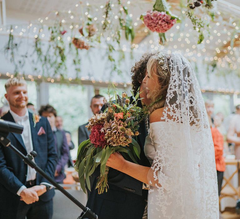 Bride & groom hug on their wedding day during ceremony as guests watch