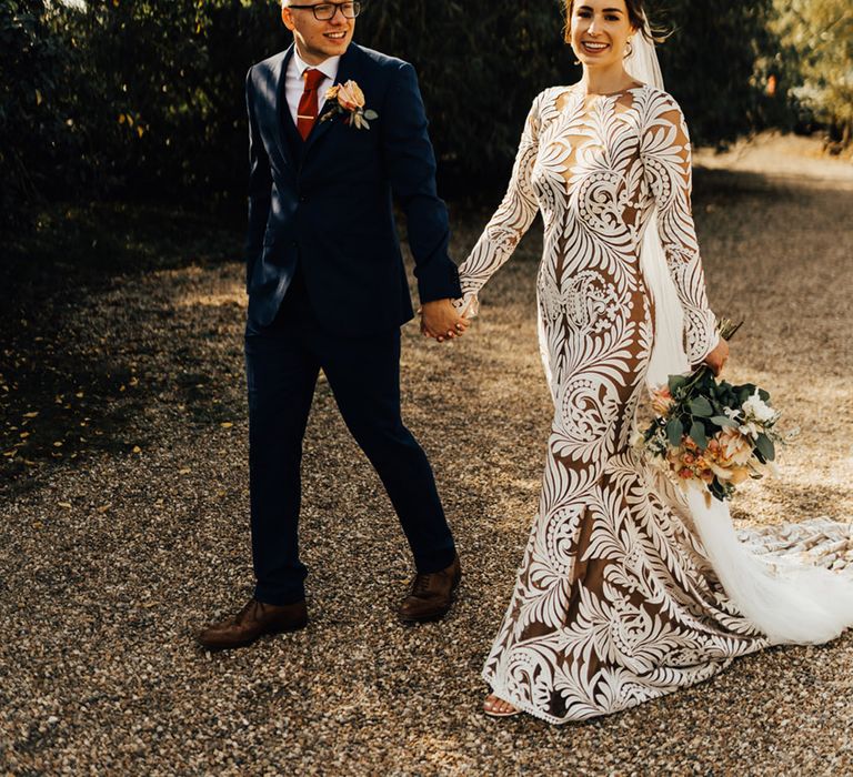 Groom with a orange autumnal accent colour tie & navy suit holds Boho bride in her Rue De Seine 