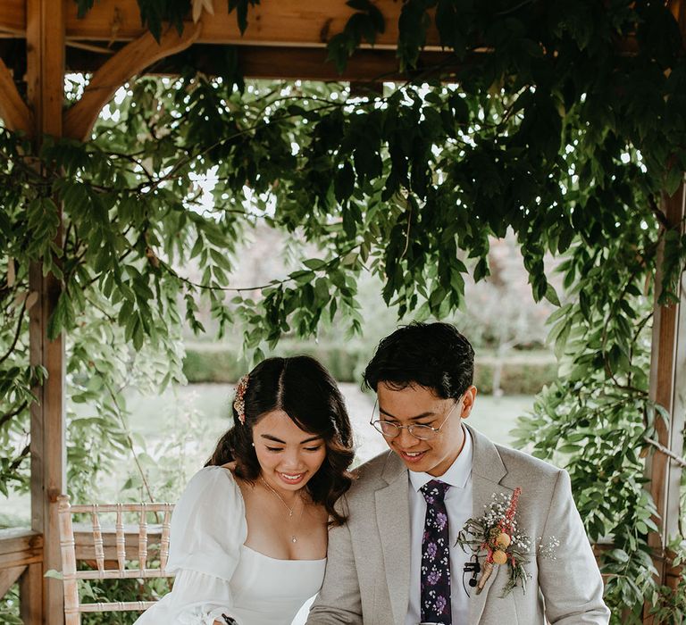 Bride & groom sit with one another as they sign marriage certificate on their wedding day