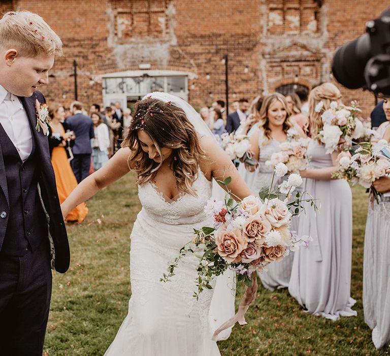 Bride looks down at her feet as she holds her grooms hand on her wedding day