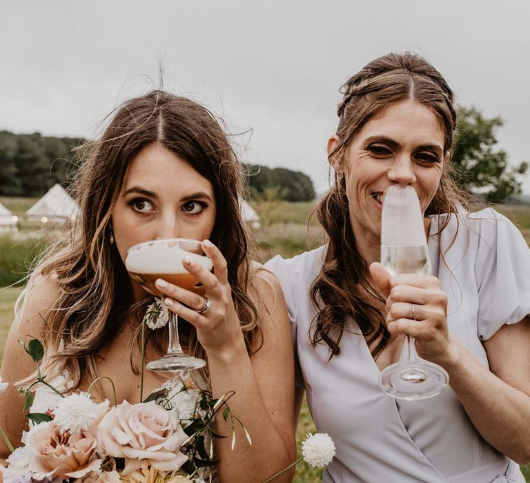 Bride drinks cocktail with her bridesmaid on her wedding day