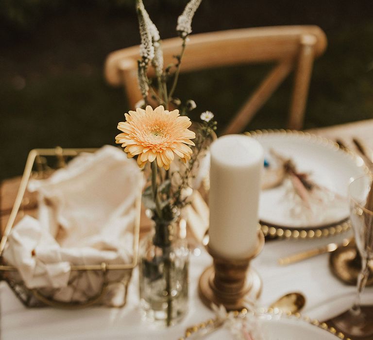 Rustic tablescape complete with gold cutlery and yellow flower