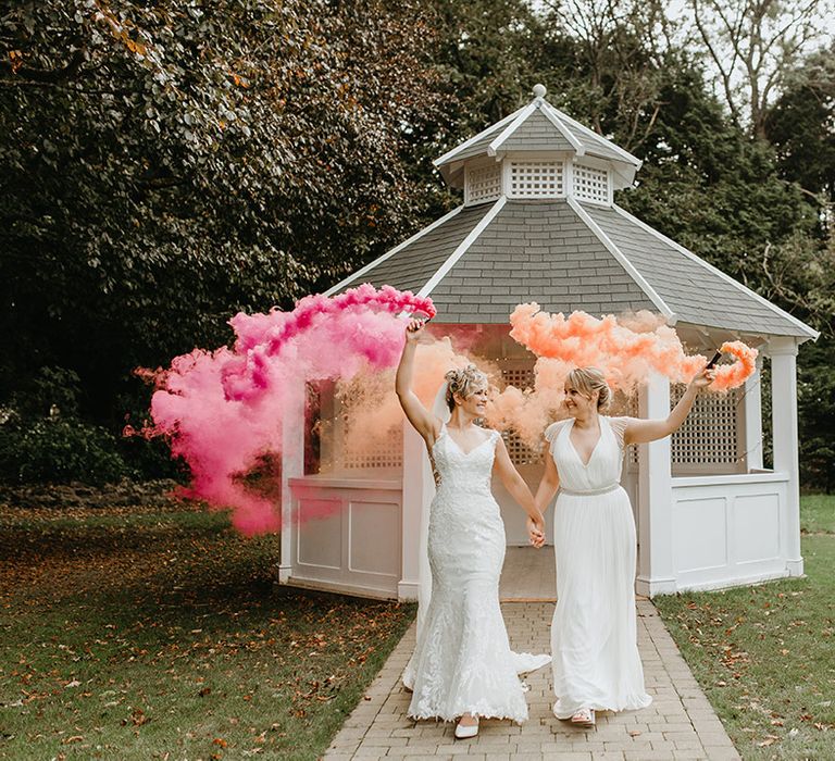 Brides hold smoke bombs on their wedding day outdoors