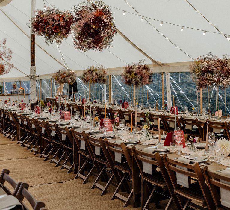 Stylish marquee wedding reception decor with gypsophila flower clouds, festoon lights and taper candles 