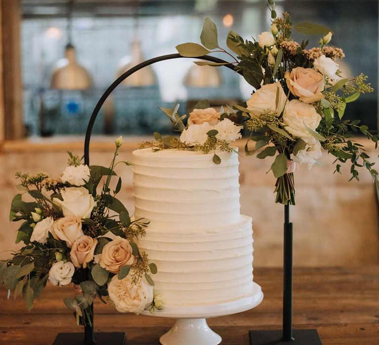 Beautiful cream wedding cake with black arch and blush flower decor