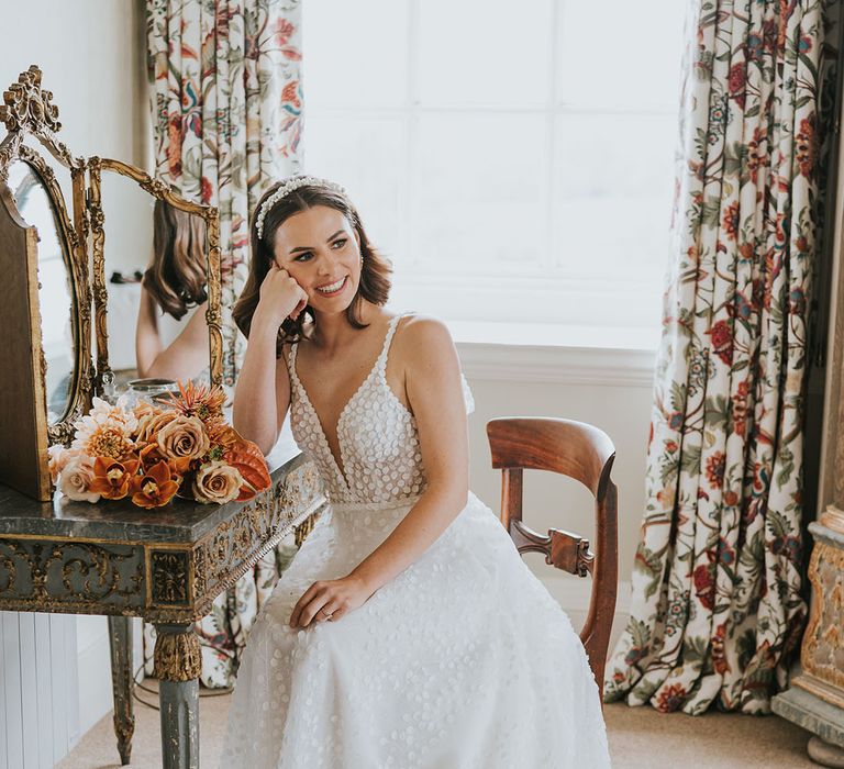 Bride in a Made With Love Wedding dress sitting at a dressing table at Kirtlington Park 