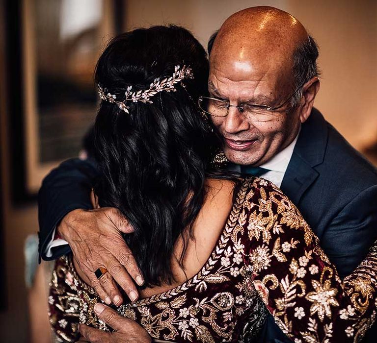 Hugs and smiles for the bride who wears flower hair piece in her dark loose curled hair 