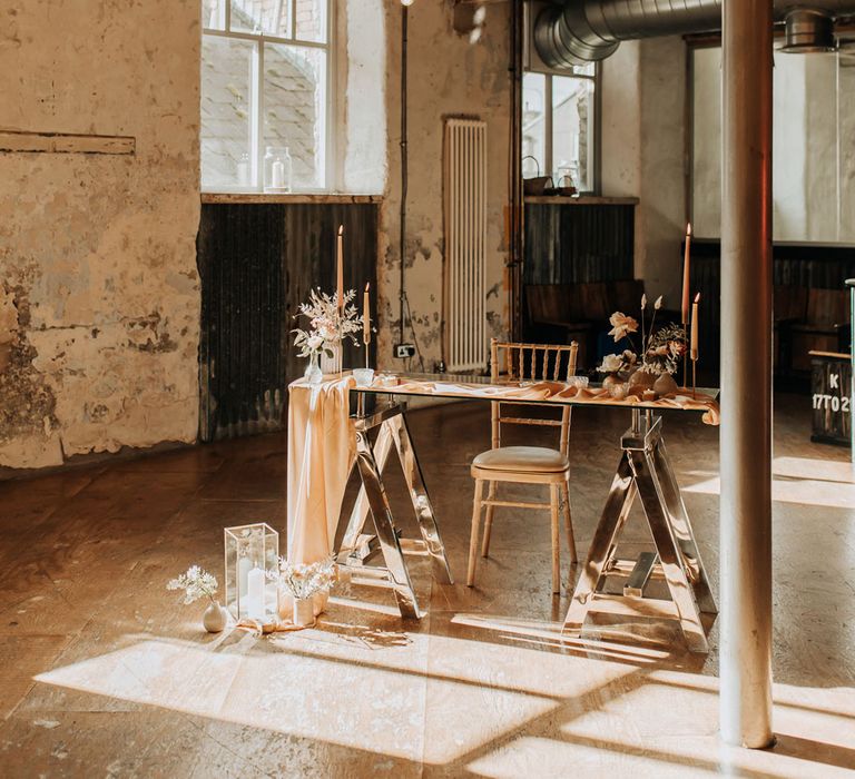 Glass wedding registry table with wooden chair, draping and candles at industrial wedding ceremony 