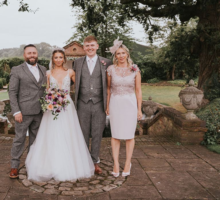 Bride and groom stand with parents on their wedding day at Micklefield Hall