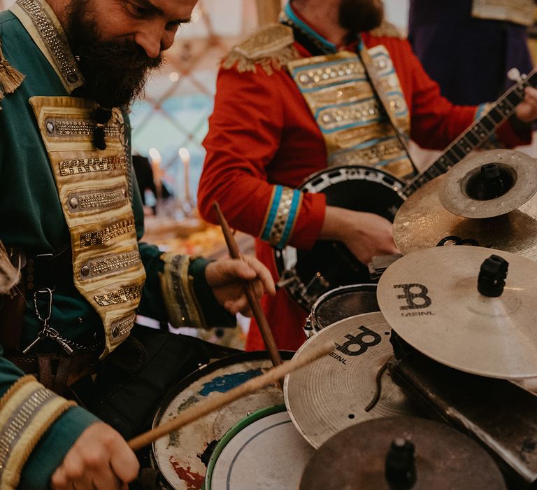 Wedding band entertainment with man in green outfit and gold turban plays the drums 