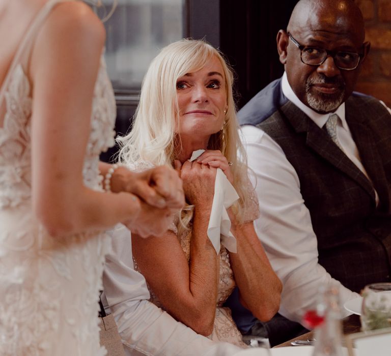 Mother of the bride looks tearily at the bride in 3D lace flower Made With Love Bridal wedding dress