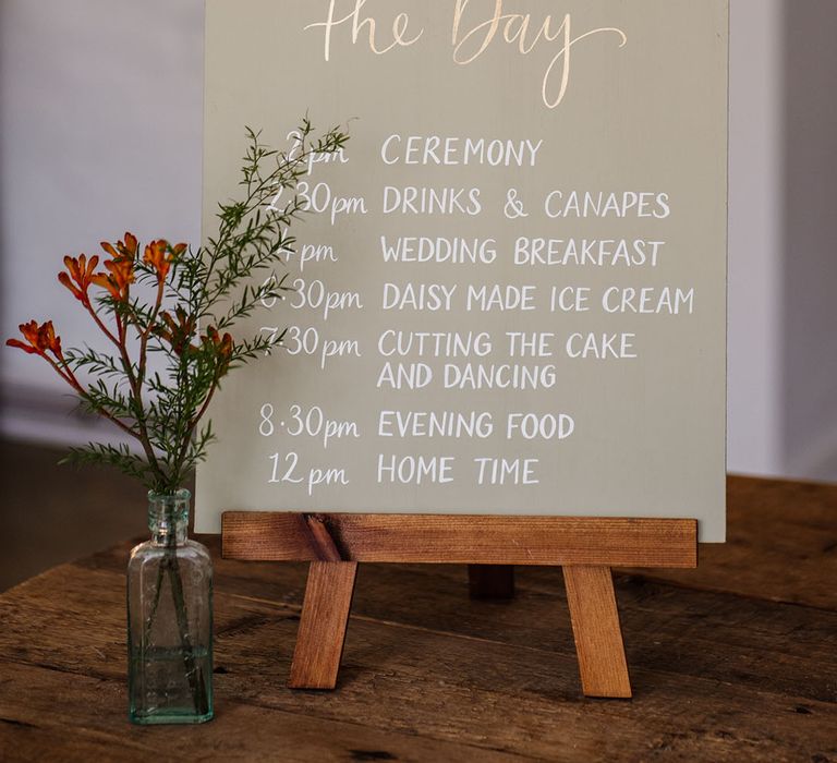 Order of the day sign with white font and small flowers 