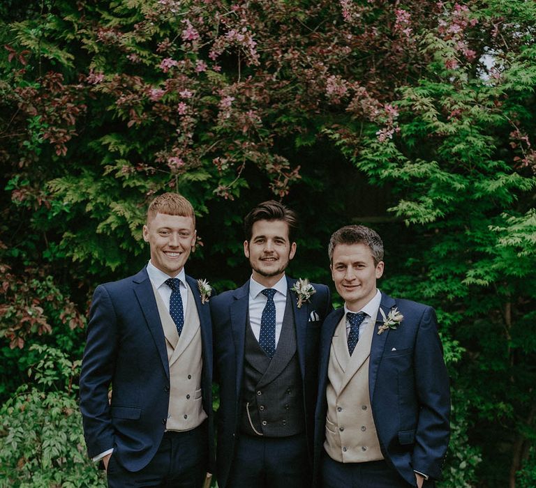 Groom in blue suit with black waistcoat with groomsmen in blue suits and beige waistcoats