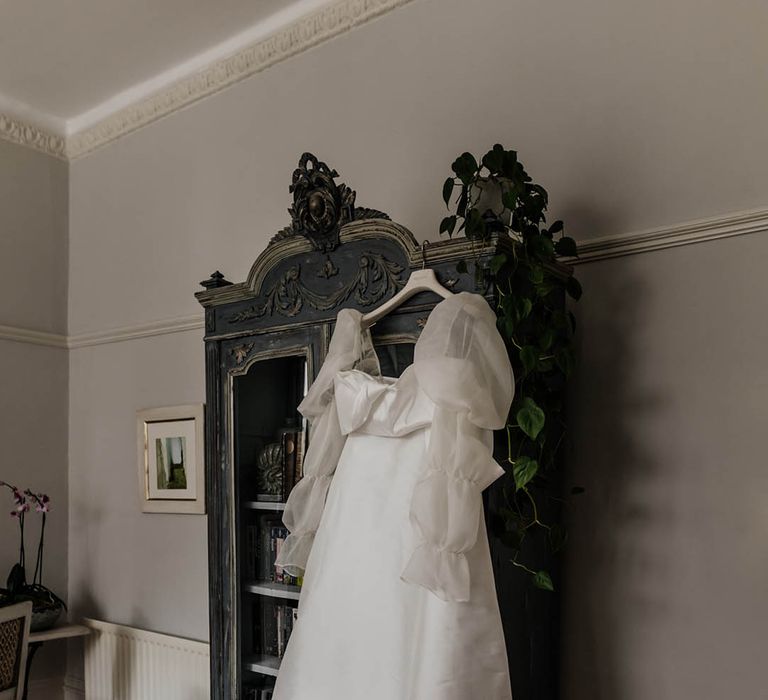 Jesus Peiro wedding dress with long sheer sleeves hanging up on the wedding morning 