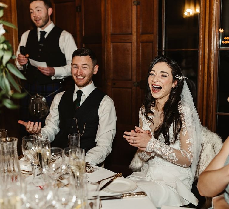 Bride & groom laugh during wedding reception speeches at Drumtochy Castle in Scotland for winter wedding