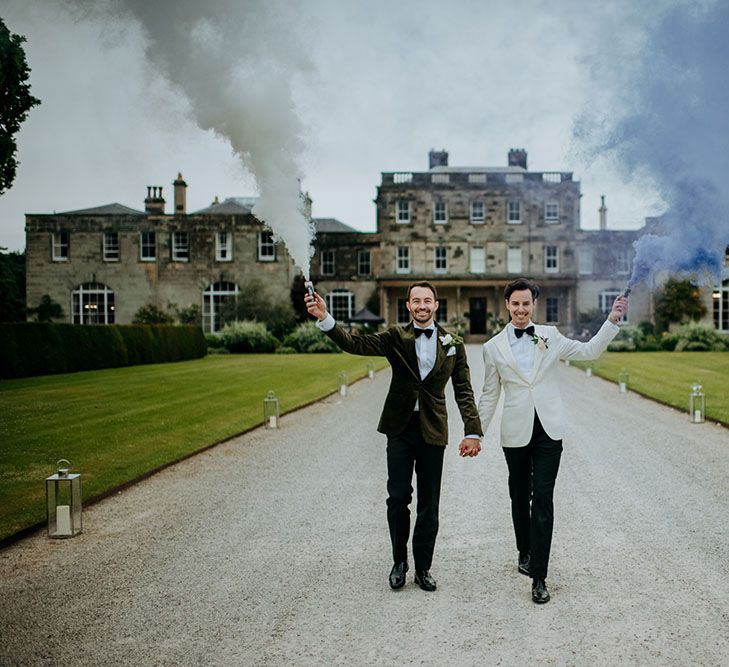 Grooms carry grey & blue smoke bombs outside Birdsall House on their wedding day