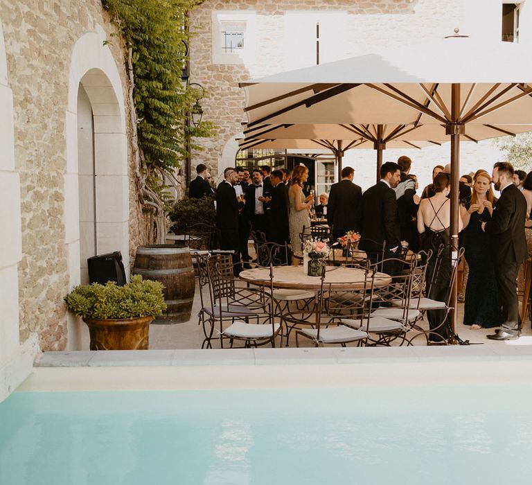 Wedding guests gather beneath umbrella's in Mas Loisonville France for outdoor wedding reception  