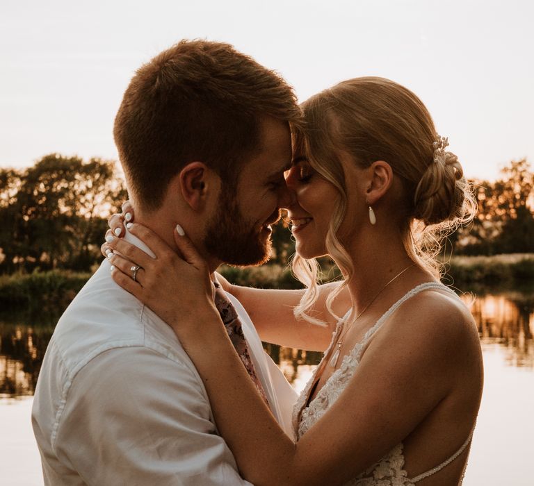 Bride & groom embrace lovingly as the sun begins to set across the Thames on the evening of their wedding day