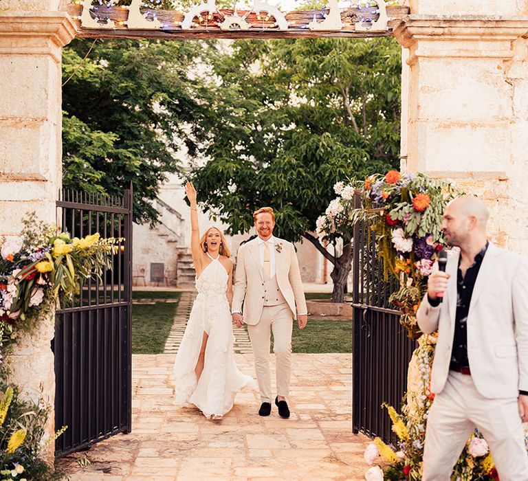 Bright and colourful flower columns decorate the entrance to the outdoor wedding reception 