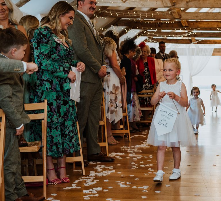 Reception room at The Green Cornwall, flower girls walking down the aisle with petals wearing white dresses and holding signs