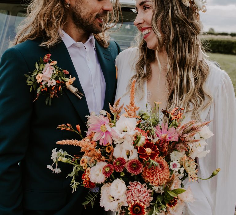 Bride holds colourful bouquet as groom wears matching floral buttonhole 