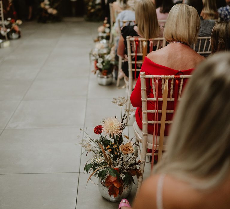 Wedding guests sitting in St Tewdrics House, Monmouthshire with colourful mixed floral bouquet decorations along the sides