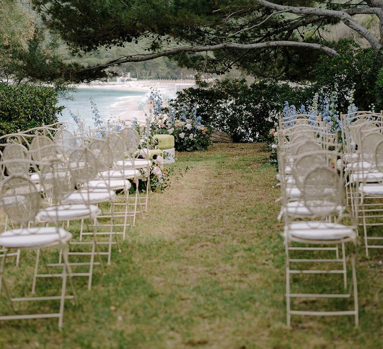 View of the sea from the aisle adorned with intricate chairs and beautiful flowers including roses, wild flowers and more