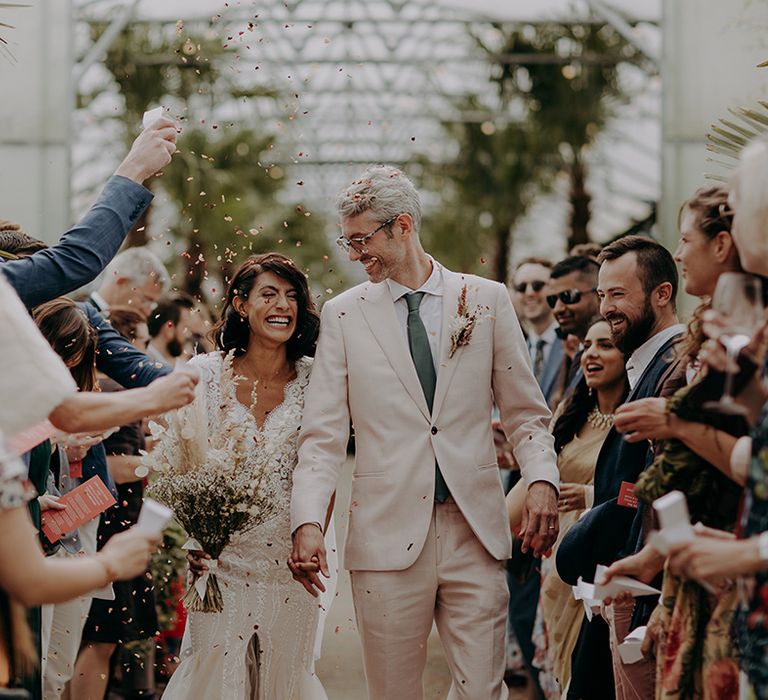 Bride and Groom walk down aisle together after ceremony with confetti