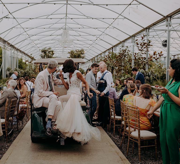 Bride and Groom sit on buggy looking behind them with brides tulle fishtail dress hanging off the edge