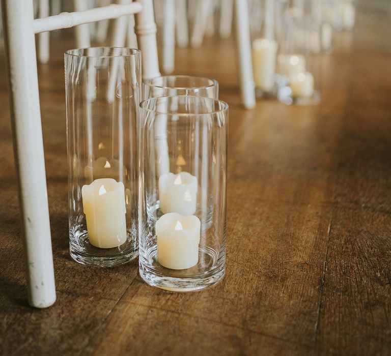 Fake pillar candles in hurricane vases decorating the aisles 