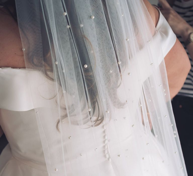 Bride wearing a pretty pearl veil in an off the shoulder wedding dress