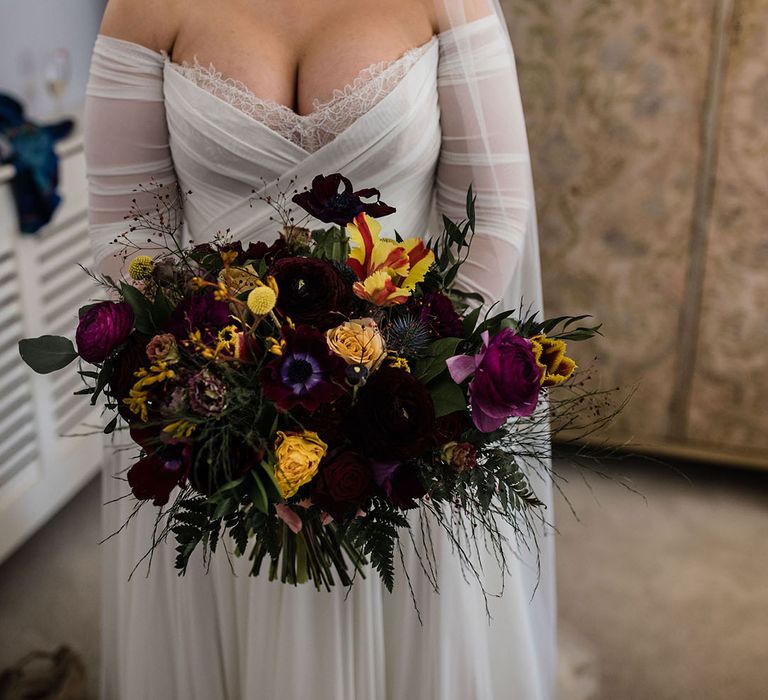 Bride in a Wtoo by Watters wedding dress holding a purple and yellow spring wedding bouquet for March wedding 