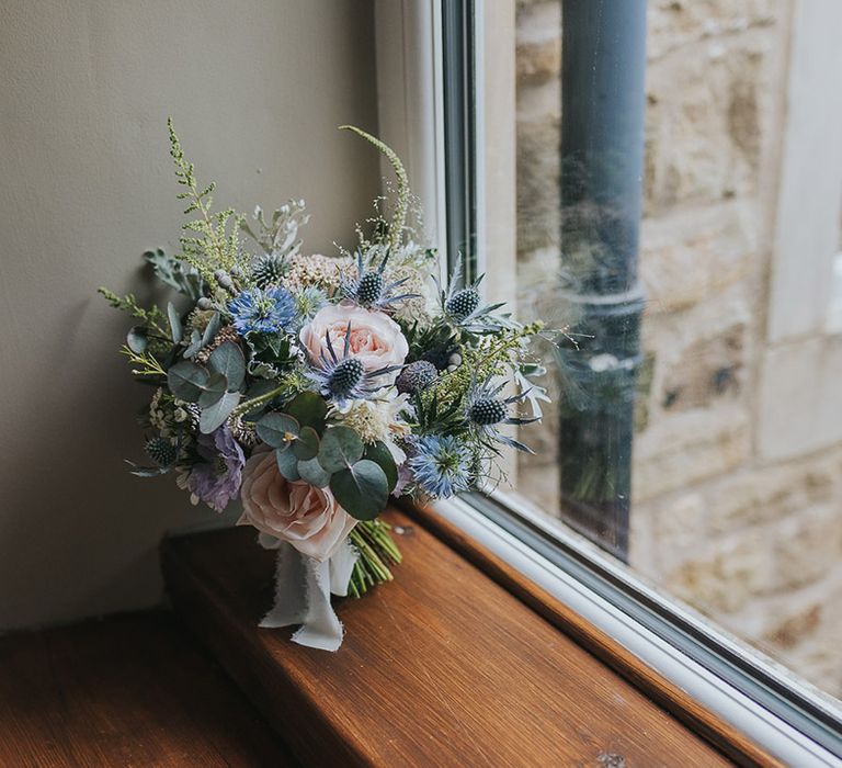 pastel pink and blue wedding bouquet with thistles and roses