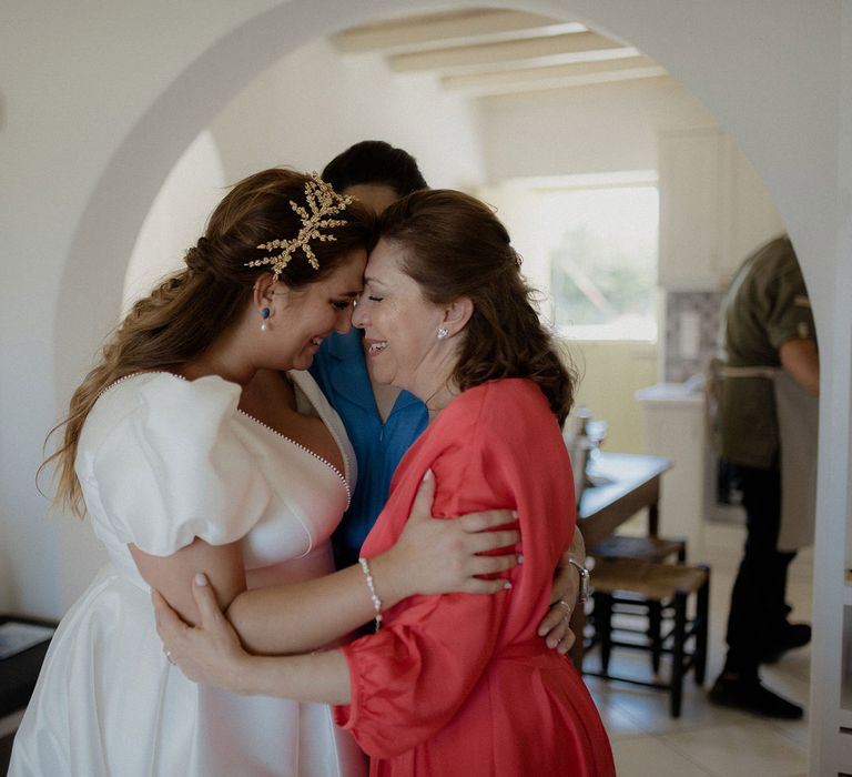 Bride in satin dress and bridal crown embracing family before wedding ceremony 