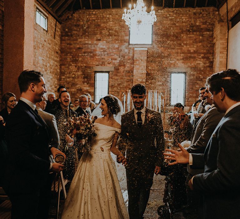 The wedding guests throw confetti over the bride and groom to celebrate the wedding 