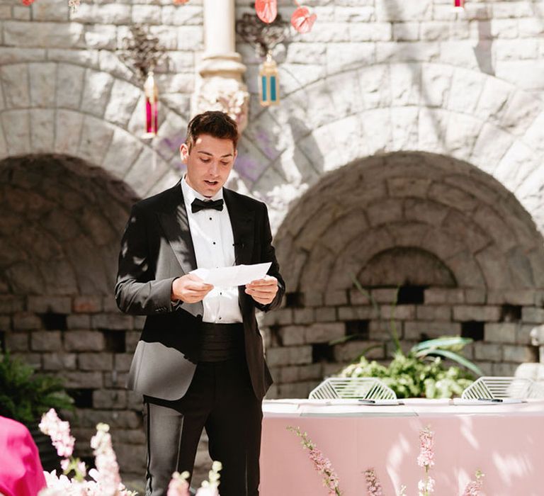 Wedding guest in black tie reads out a wedding reading during the ceremony in the Orangery at De Vere Tortworth Court