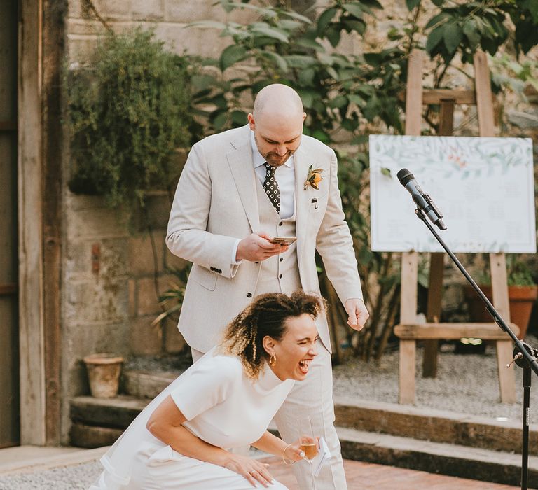 Bride and groom laugh at the wedding speeches 