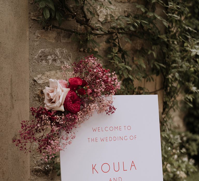 Red and pink wedding welcome sign with red and pink wedding flower decorations of roses and gypsophila 